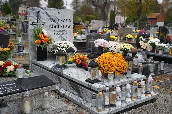 Nowoczesny nagrobek z jasnego granitu z wyraźnym czarnym użyleniem i grawerowanym krzyżem