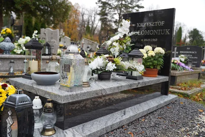 Nowoczesny nagrobek z jasnego, pasiastego granitu z grubą czarną płytą napisową i lampionami