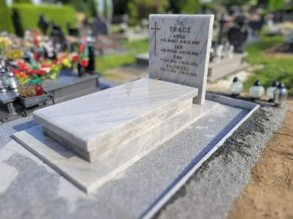 Jasny, żyłkowany nagrobek pojedynczy o nowoczesnej, prostej formie z pionową płytą napisową i grawerowanym krzyżem