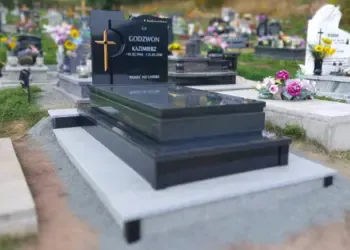 Nowoczesny nagrobek z czarnego granitu z wyciętym krzyżem i złotymi napisami