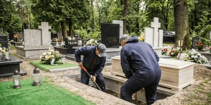 Dwóch pracowników przygotowuje grób na cmentarzu