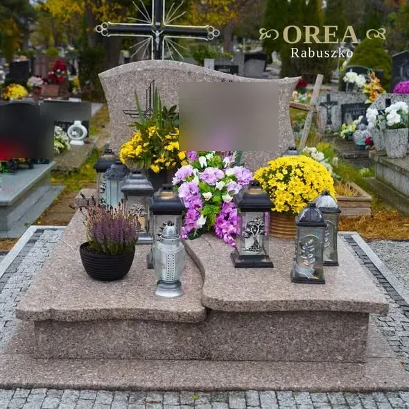 Podwójny nagrobek z granitu Cherry Pink otoczony kostką granitową, z kwiatami i zniczami