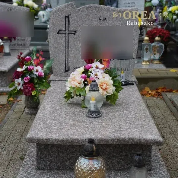 Pomnik pojedynczy z brązowego granitu widziany od przodu, z kwiatami i zniczem na nakrywie