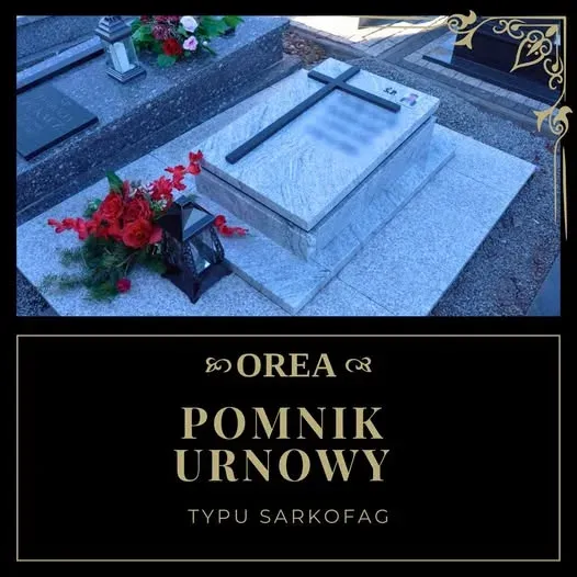 Pomnik urnowy typu sarkofag z jasnego granitu Viscont White z czarnym krzyżem, na cmentarzu wśród czerwonych kwiatów